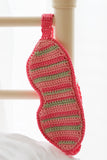 A crocheted sleep mask hanging on a bed post