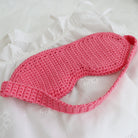 A crocheted sleep mask on a bed