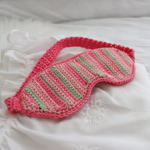 A crocheted sleep mask on a bed